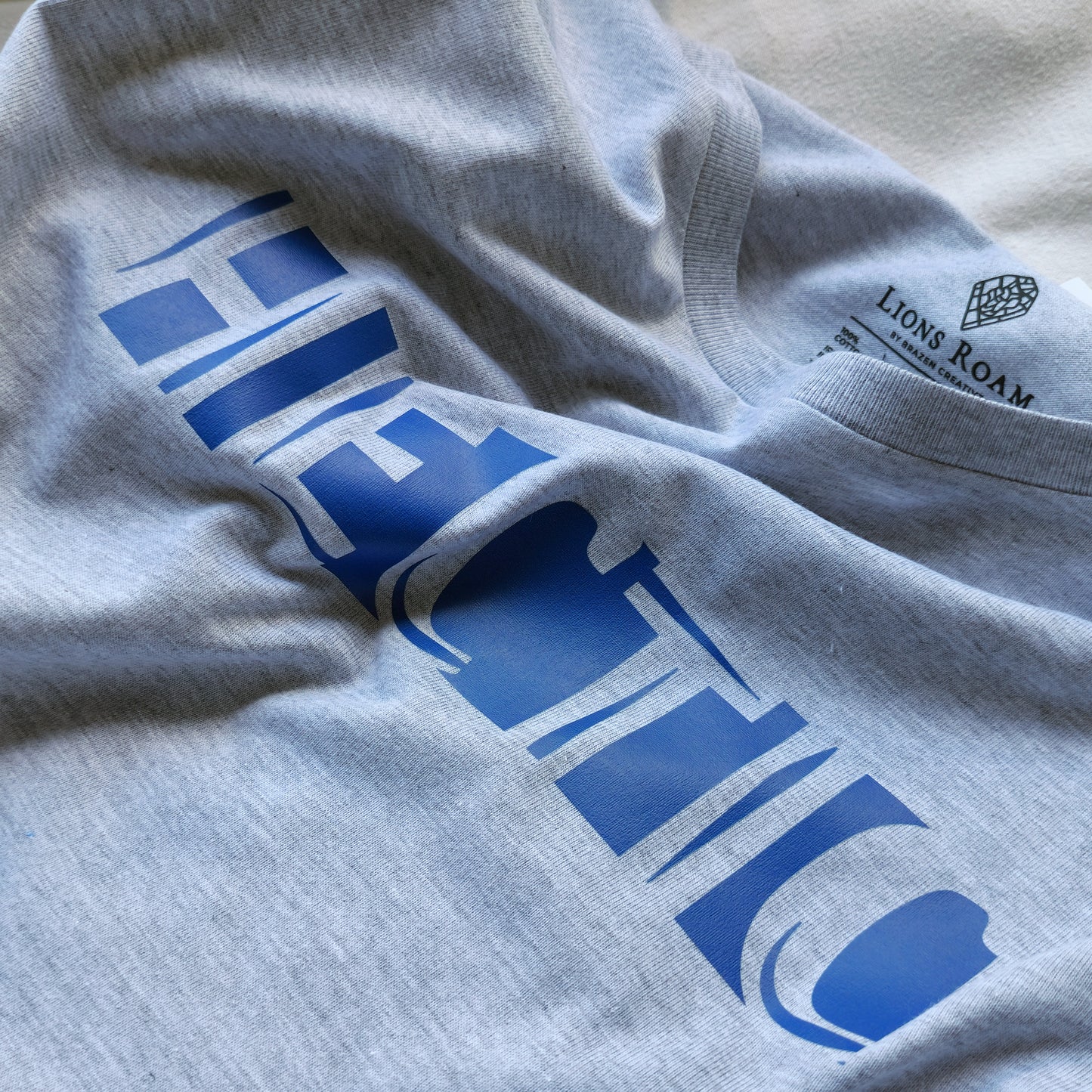 A Grey t-shirt with the phrase "Hectic" printed in Blue.