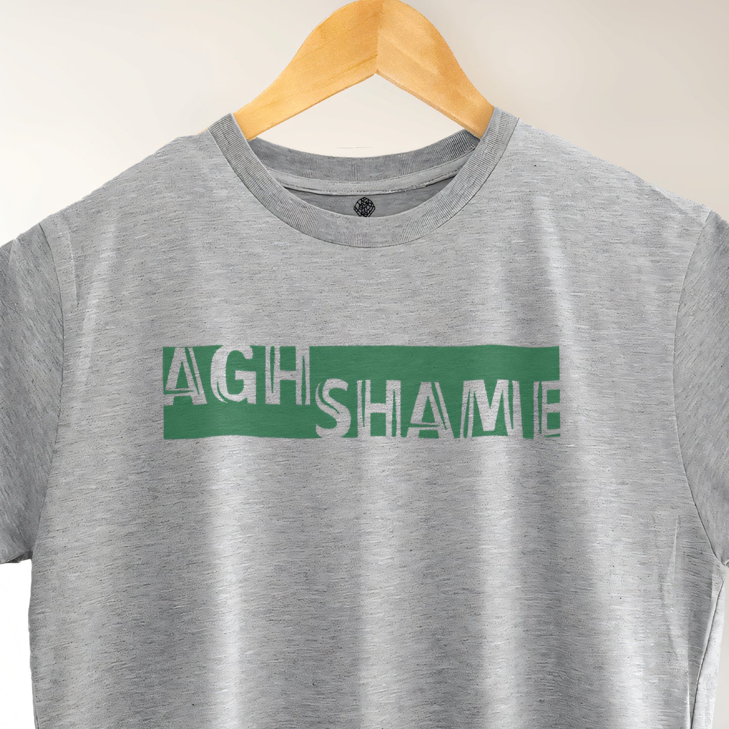 A Grey t-shirt with the phrase "Agh Shame" printed in Green.