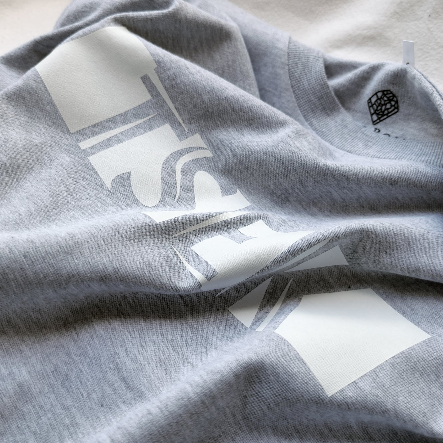 A Grey t-shirt with the phrase "Tsek" printed in White.