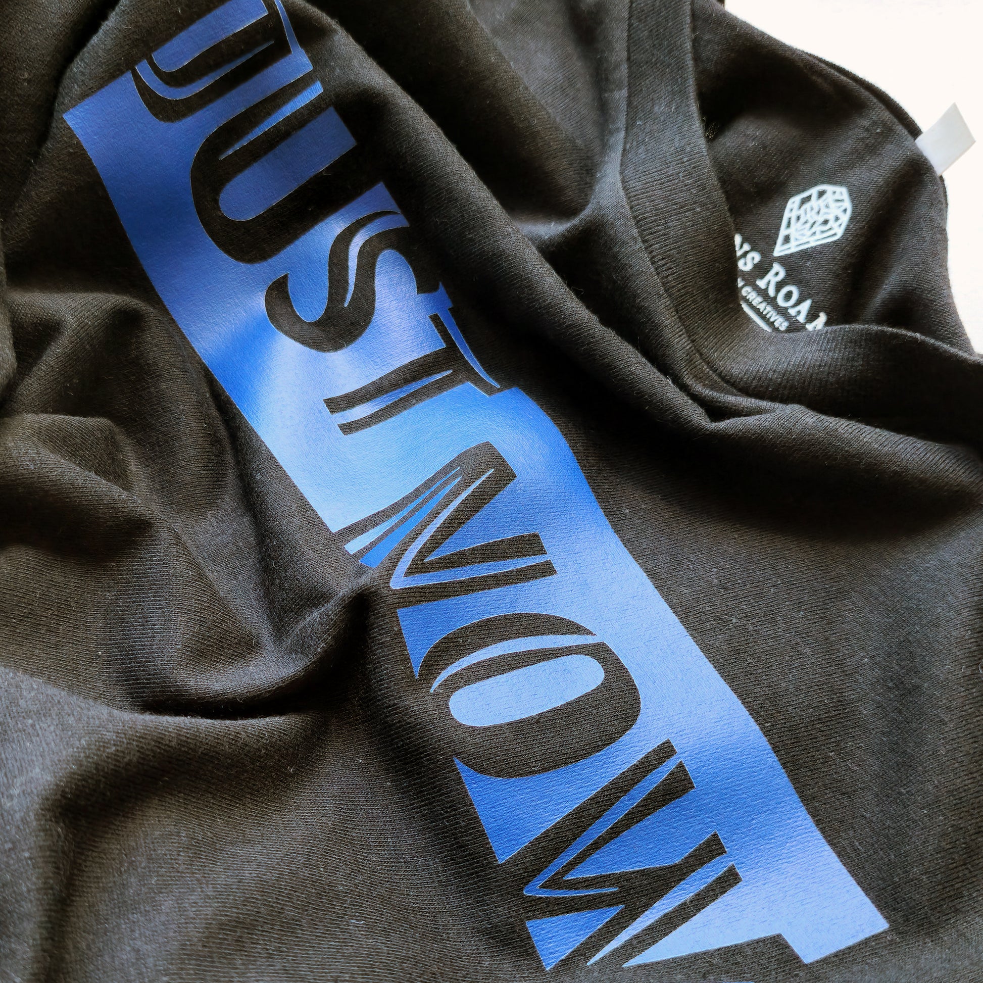 A black t-shirt with the phrase "Just Now" printed in Blue.