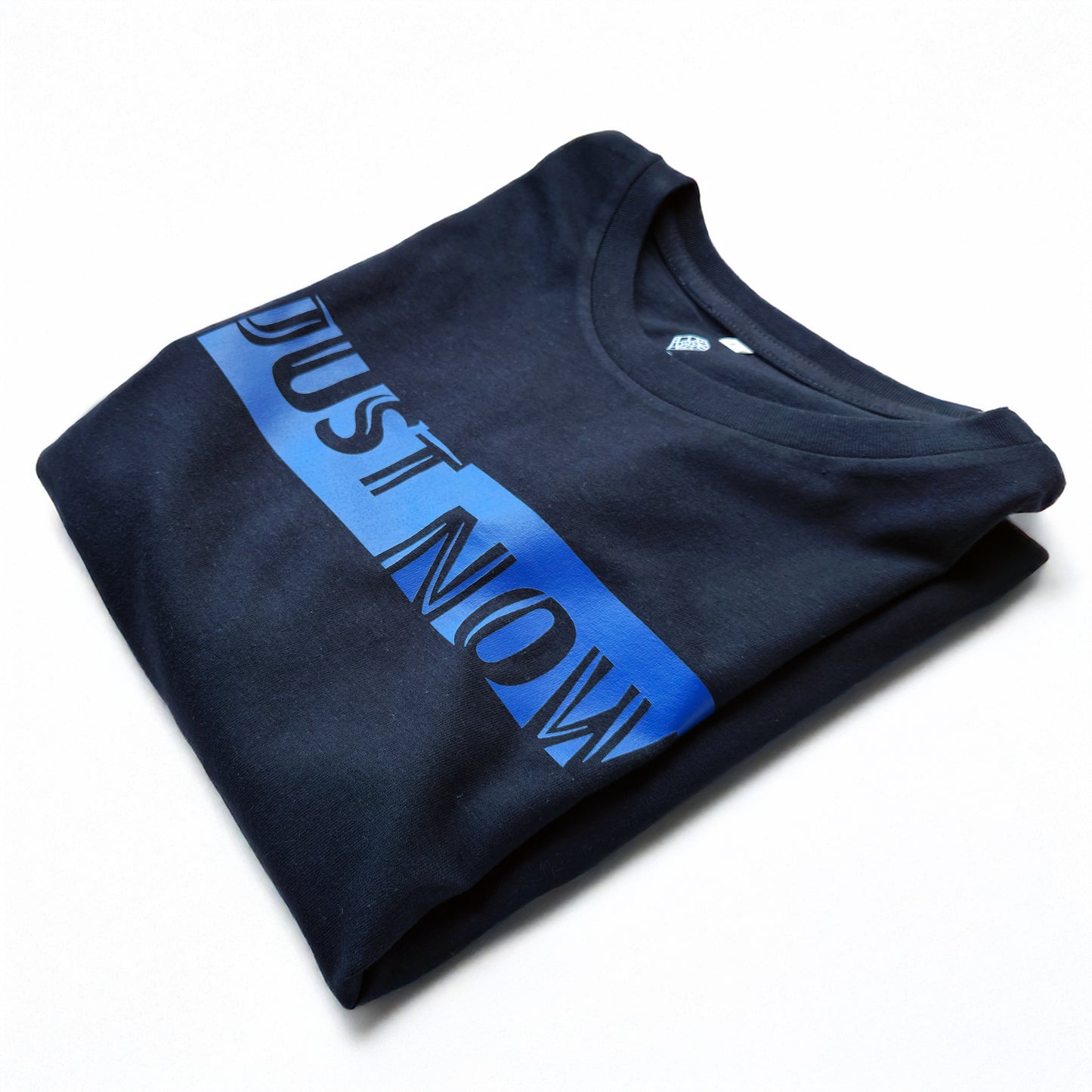 A black t-shirt with the phrase "Just Now" printed in Blue.