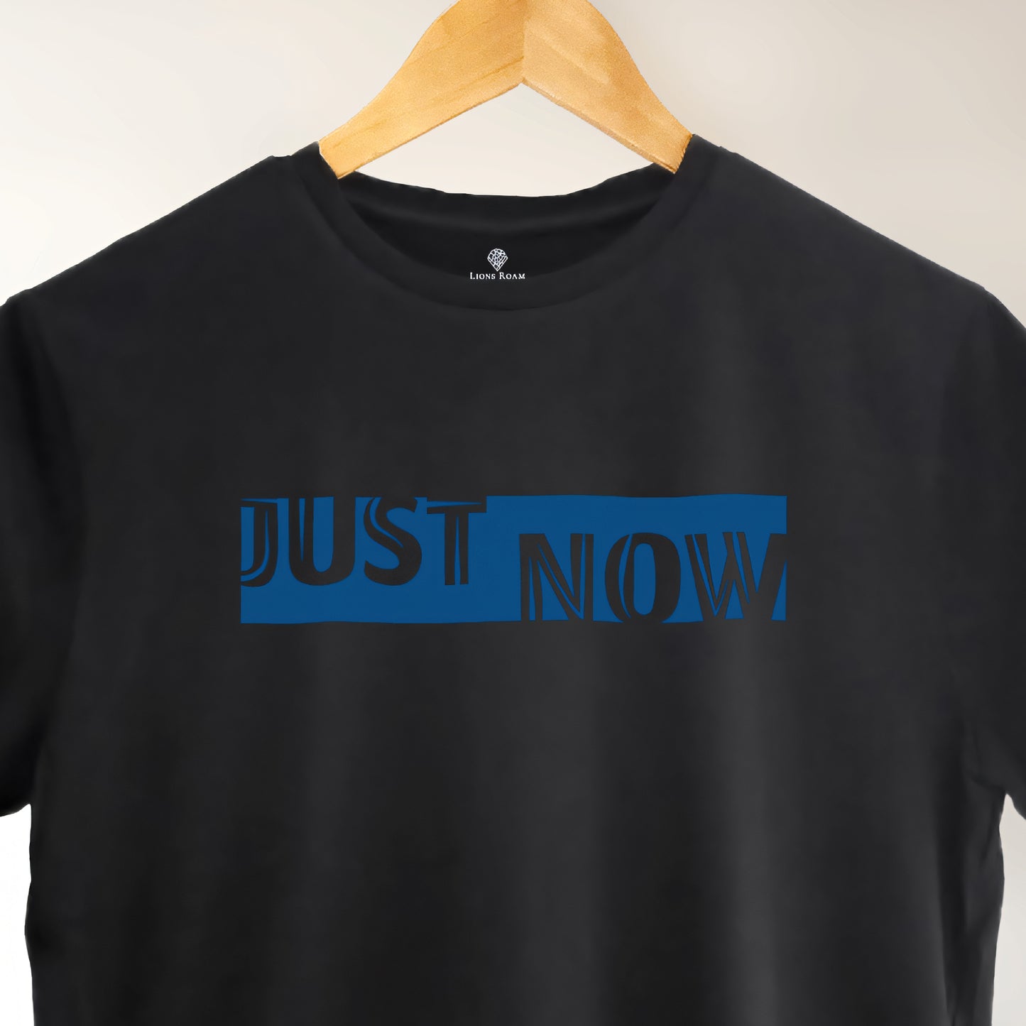 A black t-shirt with the phrase "Just Now" printed in Blue.