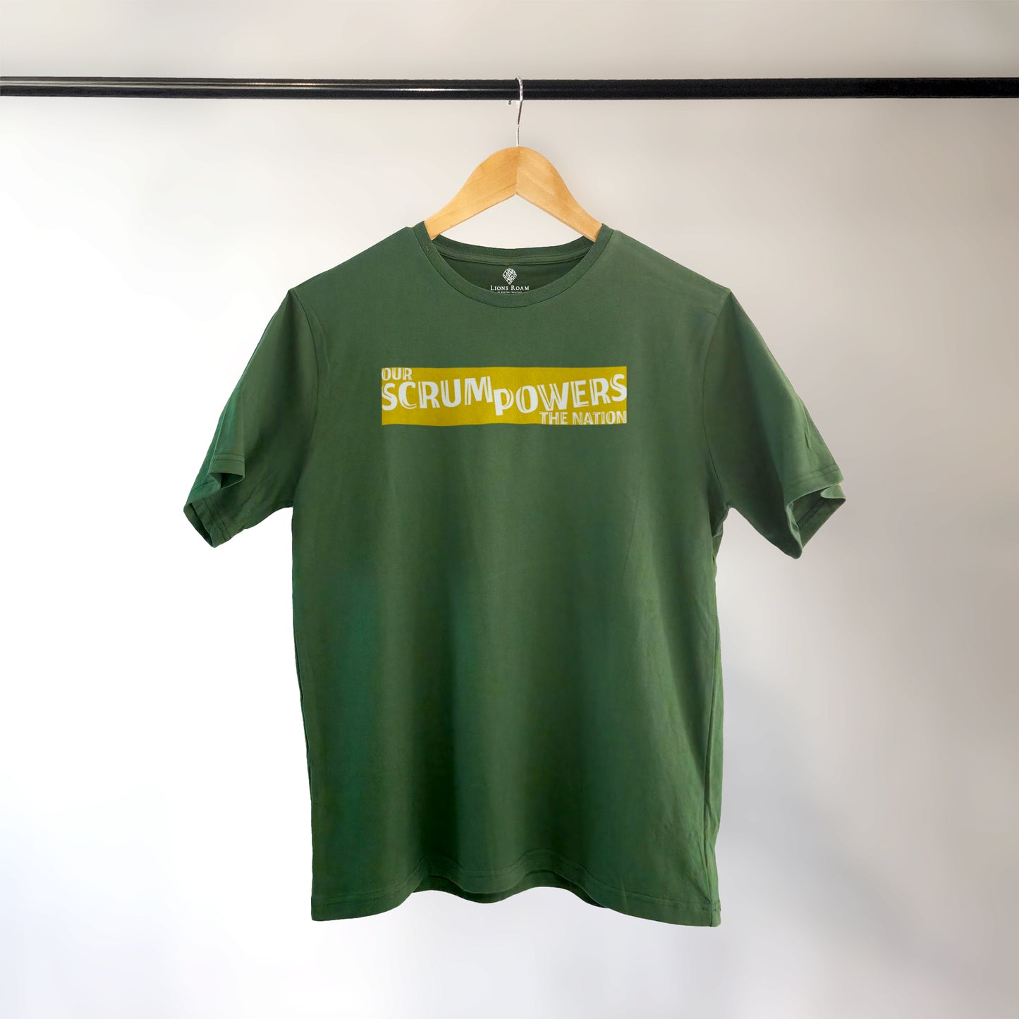 Green Lions Roam t-shirt with the phrase 'Our Scrum Powers the Nation' displayed on a hanger against a neutral background. The bold design makes a witty reference to South African resilience and rugby pride.
